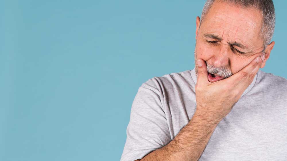 A man holding his jaw in pain.