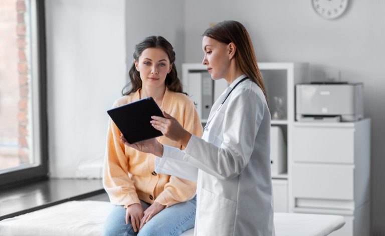 A dentist showing a woman an image on an ipad. Contact us today for an appointment.